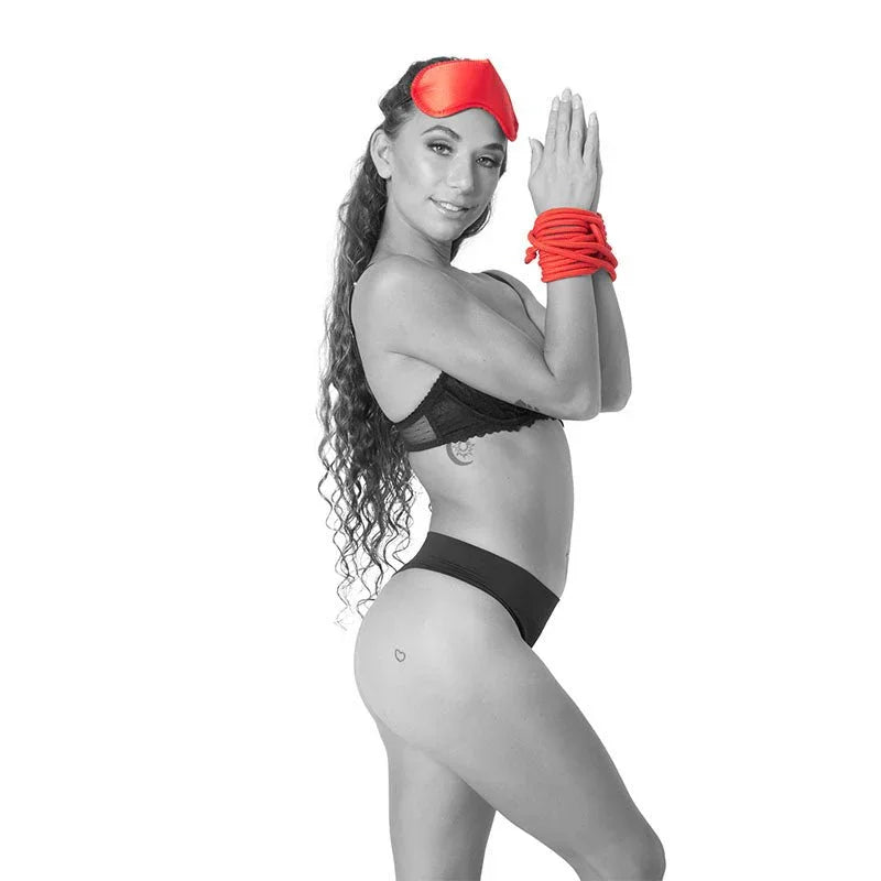 Model wearing a red blindfold with her wrists bound in the red rope