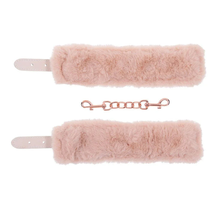 The two peach fur cuff linings laid apart with the rose gold chain between them