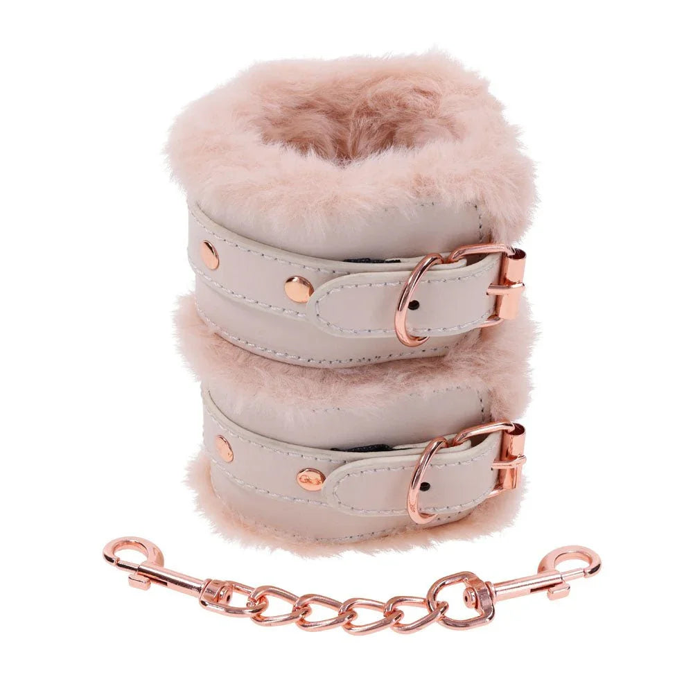 Fur handcuffs stacked one above the other, rose gold chain and clips below