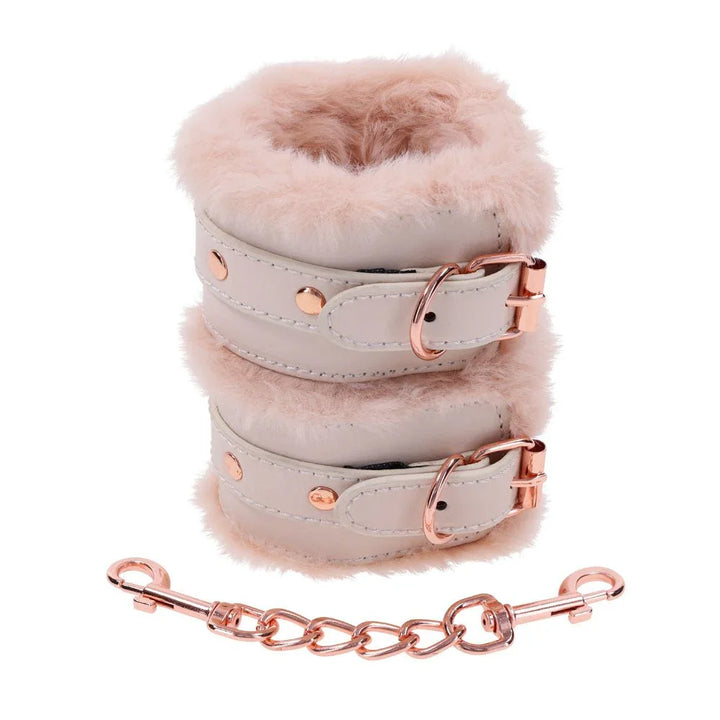 Fur handcuffs stacked one above the other, rose gold chain and clips below