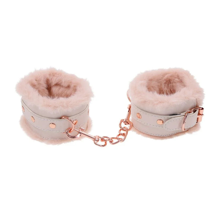 Cream fur-lined handcuffs standing upright, joined by a rose gold chain