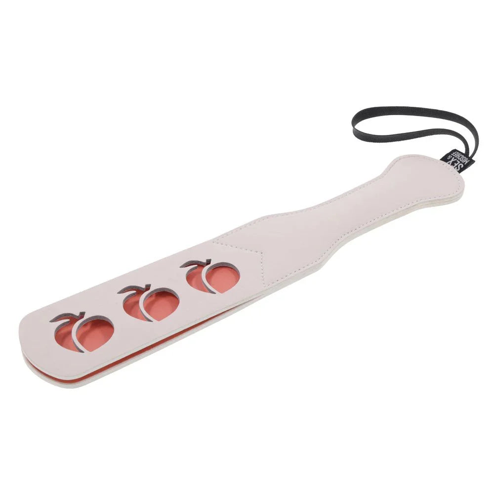 Peach impression paddle angled with the blade lower left and the handle above