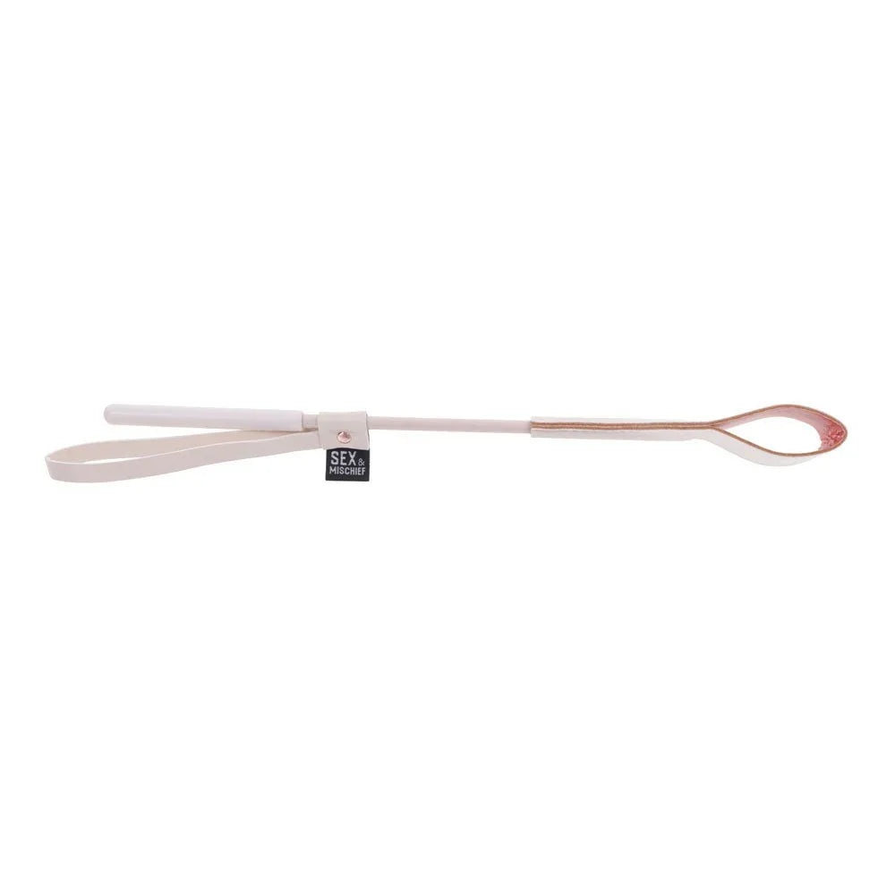 Peach riding crop laid flat, thin shaft between the tip and the wrist loop