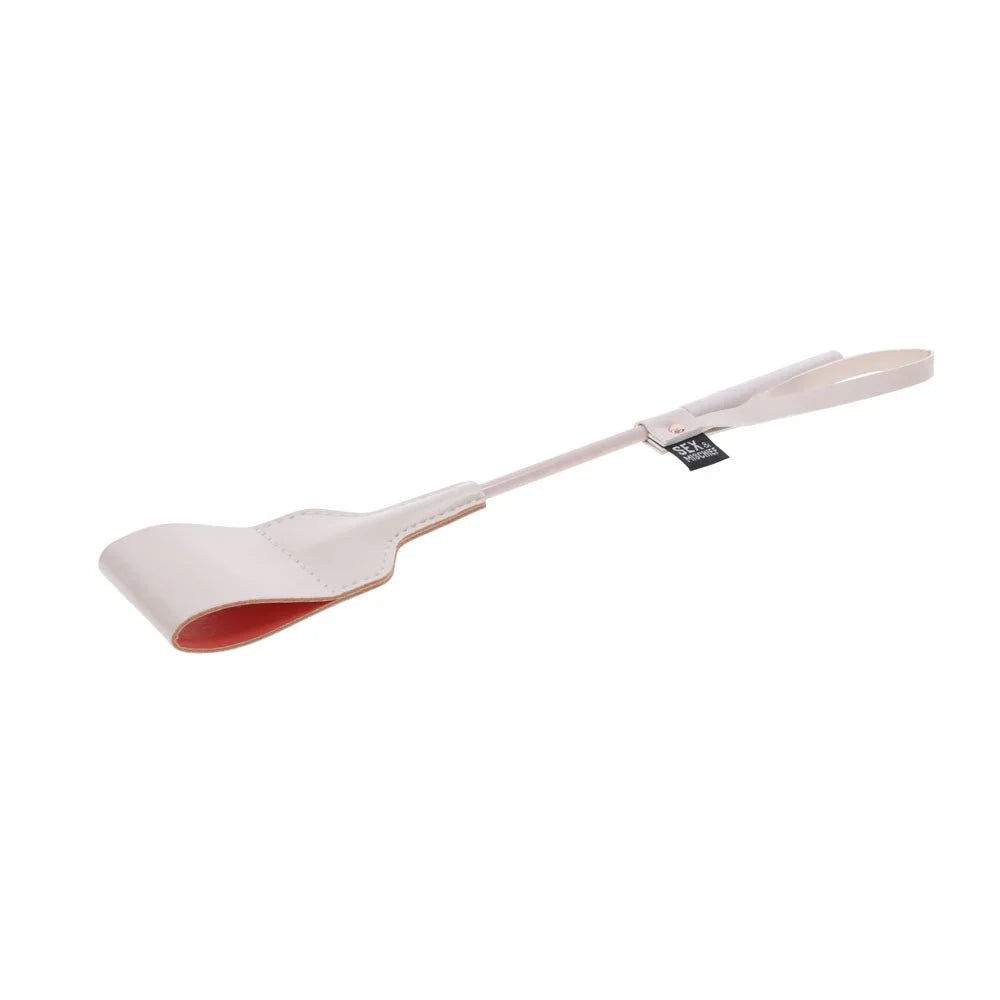 Peach riding crop tilted with the curled tip lower left and the loop at right