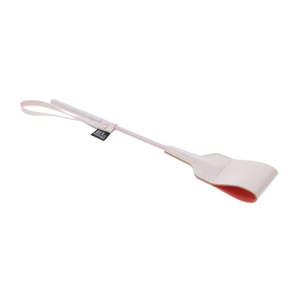 Peach riding crop laid diagonally, wrist loop upper left and tip lower right