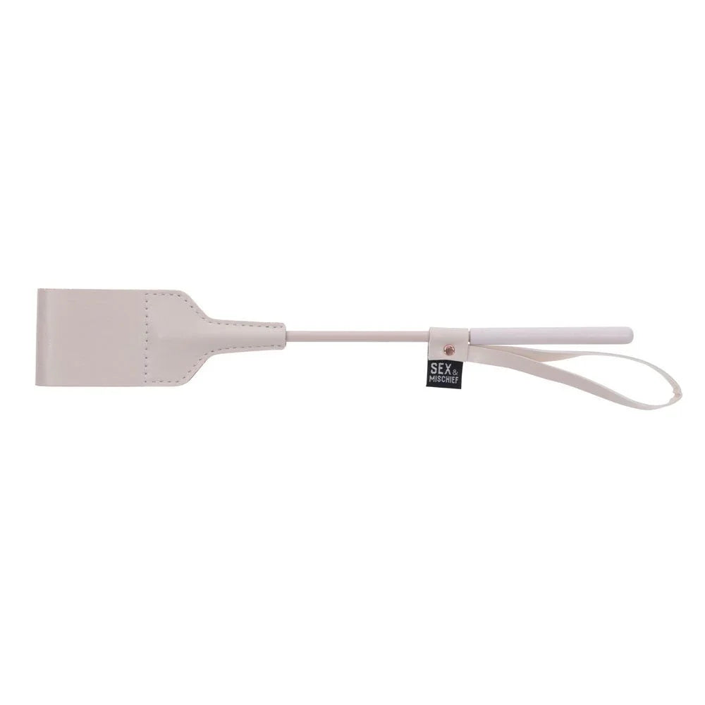 Peach riding crop laid horizontally, flat square tip at left and wrist loop at right