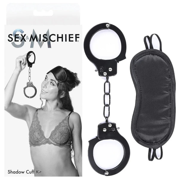 Sex & Mischief Shadow Cuff Kit card beside the black metal handcuffs and satin blindfold
