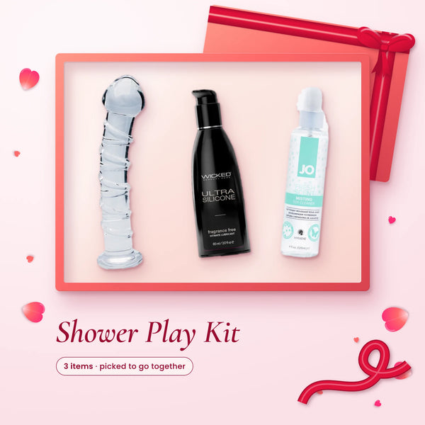 Shower Play Kit: a clear spiral glass dildo, Wicked Ultra silicone lube and JO misting toy cleaner on a pink backdrop