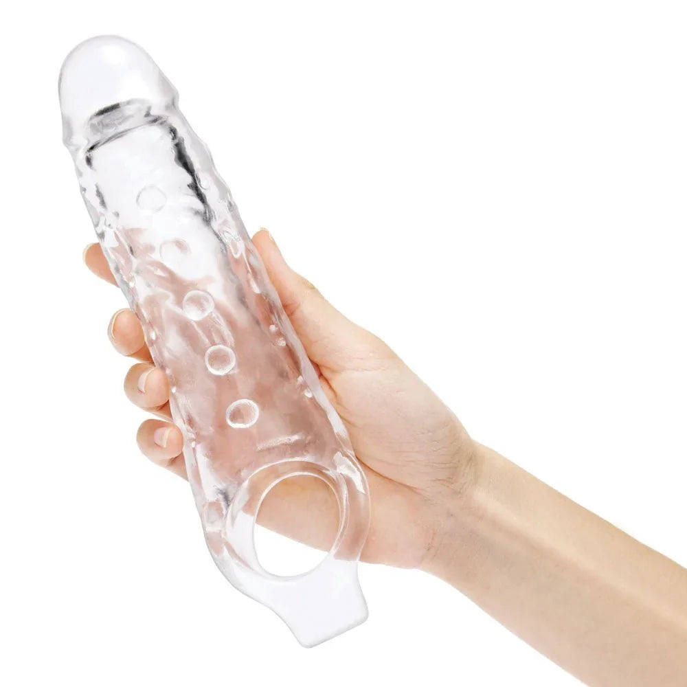 A hand holding the clear Size Up 1 inch extender, ball loop hanging below