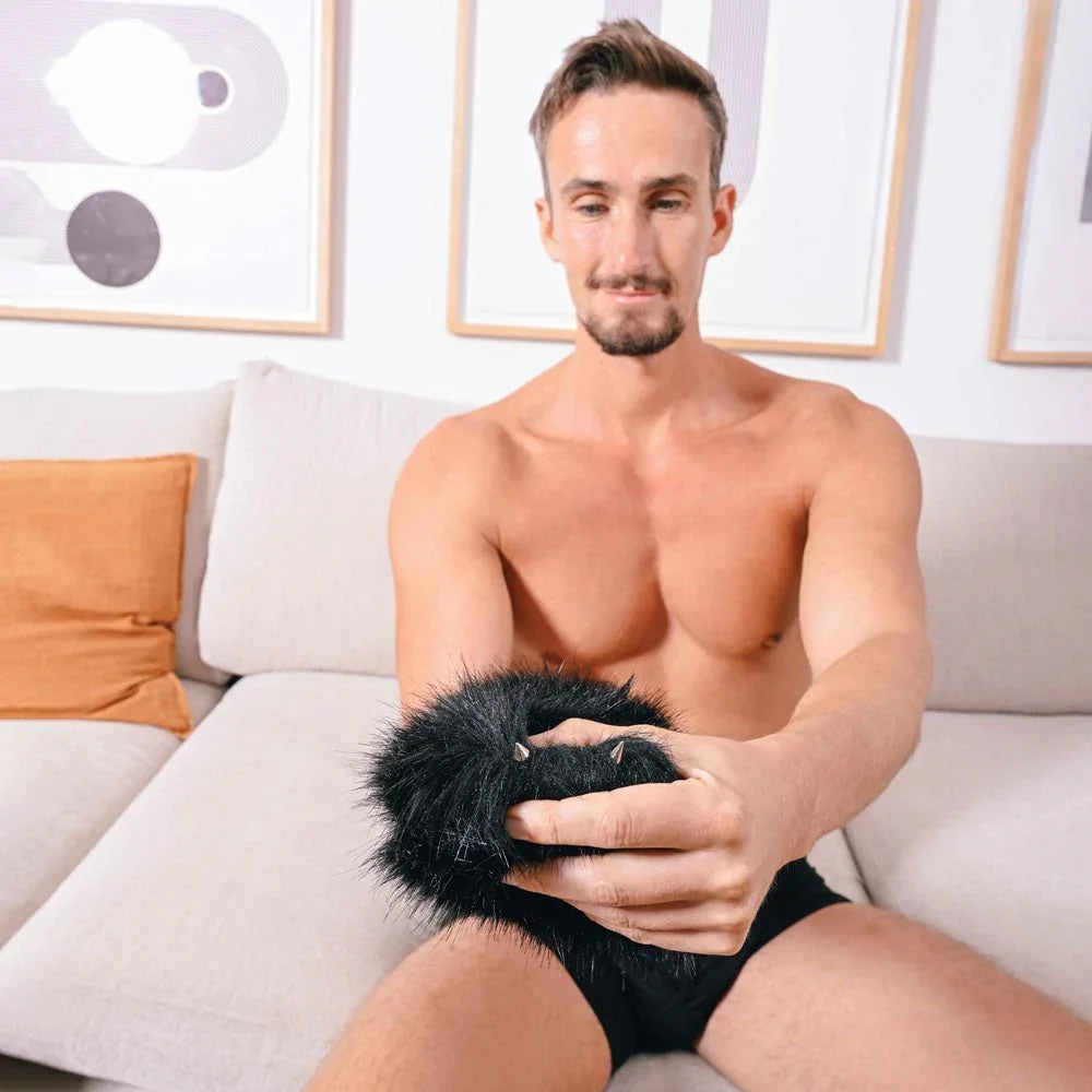 Man seated on a sofa wearing the black fur sensory mitt