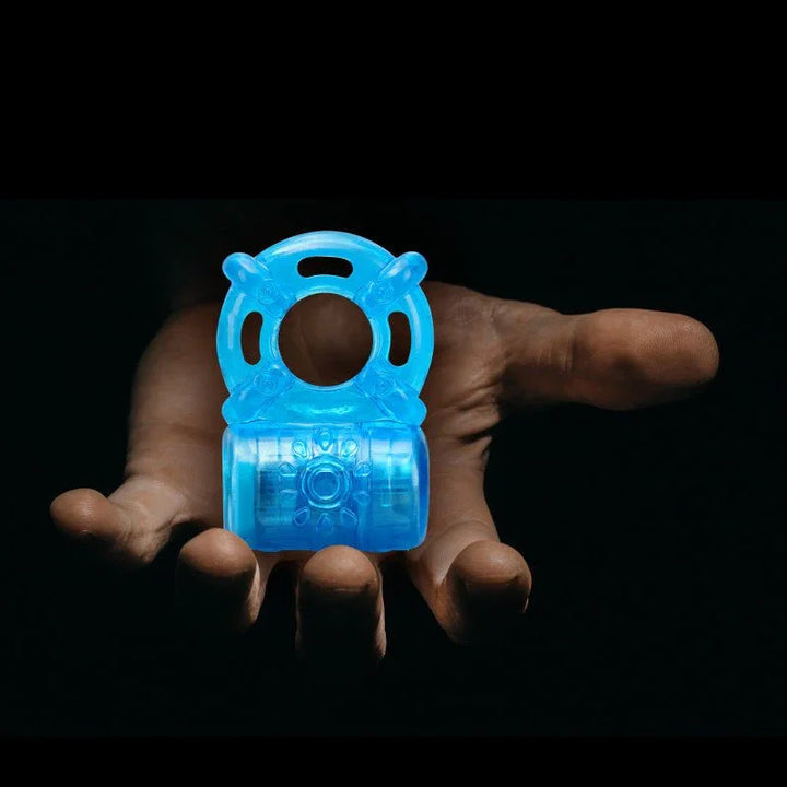 Blue Stay Hard rechargeable cock ring held in an open hand against a dark background