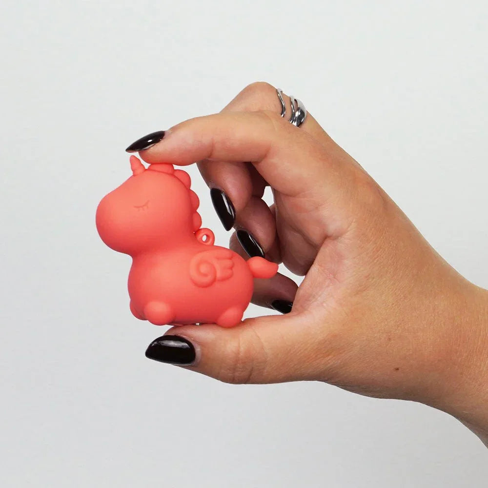 Peachy Pony mini vibe pinched between finger and thumb for scale