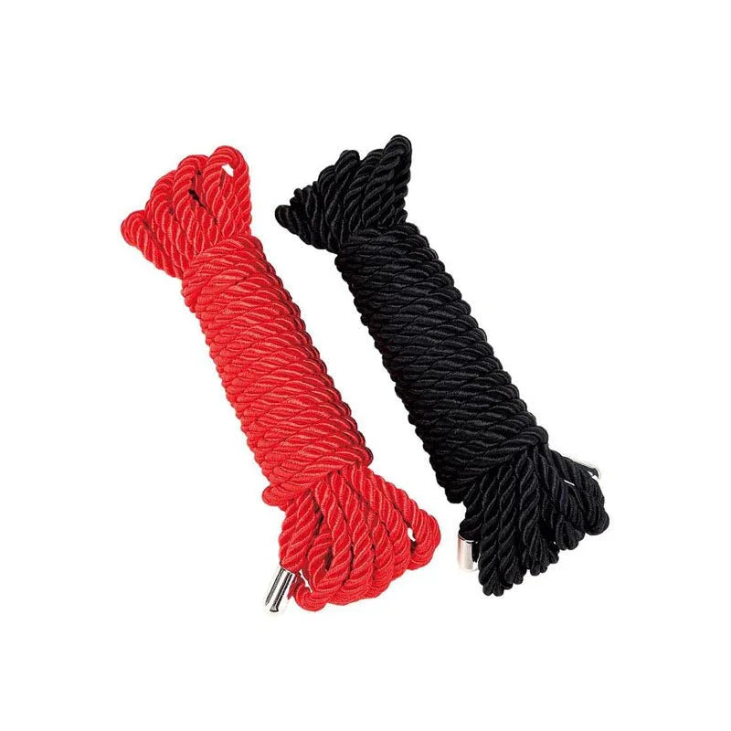 Two hanks of satin bondage rope on white, one red and one black, ends capped in metal